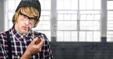 Hipster smoking pipe against window