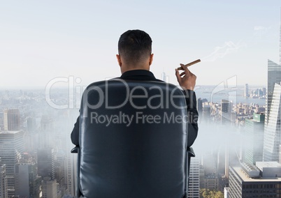 Rear view of businessman sitting on chair and looking at city while smoking cigar