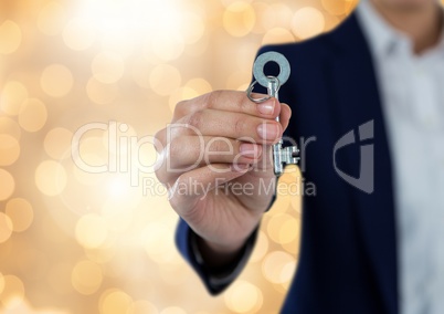 Hand holding key with sparkling light bokeh background