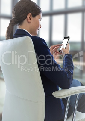 Seated business woman with phone in blurry office