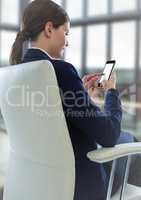 Seated business woman with phone in blurry office