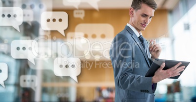 Businessman holding tablet with apps chat messages in large modern hall