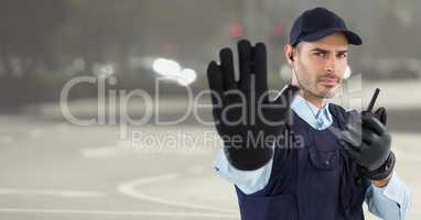 Security guard with walkie talkie and hand up against blurry street