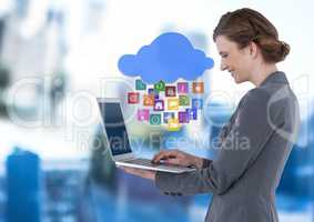Businesswoman holding laptop with cloud apps icons in blue motion public space