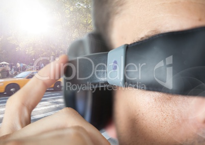 Close up of VR headset on man against sunny street with flares