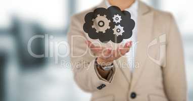 Business woman mid section with hand out and cloud with gears graphic against blurry grey office