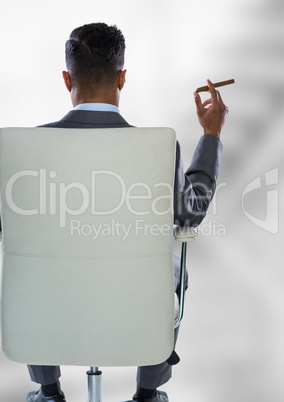Back of seated business man smoking cigar against blurry grey stairs