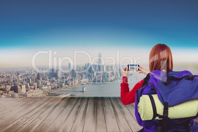 Woman traveler taking photo with her smartphone against cityscale background