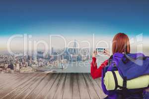 Woman traveler taking photo with her smartphone against cityscale background