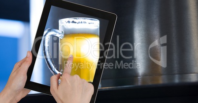 Hand taking picture of beer glass through digital tablet