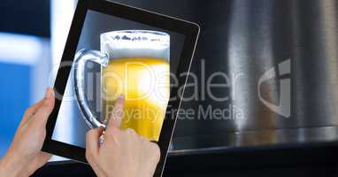 Hand taking picture of beer glass through digital tablet