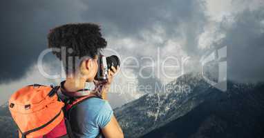 Rear view of hipster taking pictures of mountains against cloudy sky
