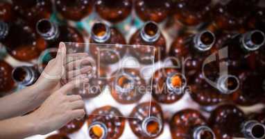 Directly above shot of hand taking picture of alcohol bottles through transparent device at brewery