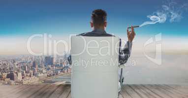 Rear view of businessman sitting on chair and looking at sea while smoking cigar