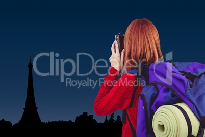 woman tourist wearing a bag is taking a picture against city Paris background