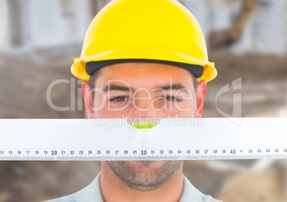 Construction Worker with spirit level in front of construction site