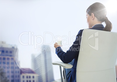 Back of seated business woman drinking against blurry buildings and flare
