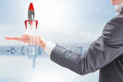 A businessman is holding a rocket taking off from his hand against blue background