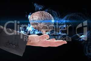 Businessman's hand is holding a brain against black abstract background