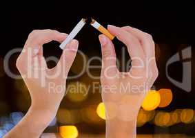 Hand ripping cigarette to quit smoking with sparkling light bokeh background