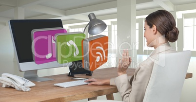 Businesswoman on computer at desk with apps icons in office