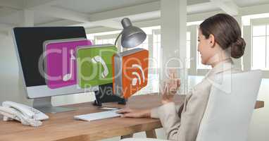 Businesswoman on computer at desk with apps icons in office