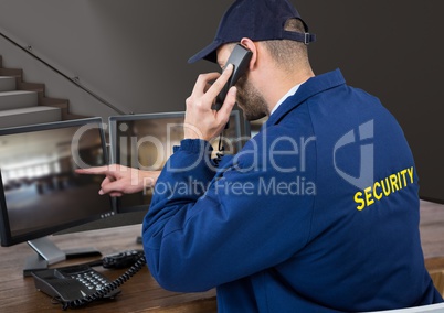 Security guard in his office phoning and pointing something in the screen