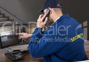Security guard in his office phoning and pointing something in the screen