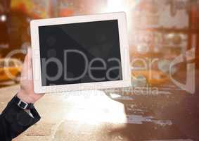 Hand with tablet against blurry street with bokeh and flares
