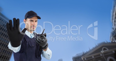 Portrait of security guard showing stop gesture while holding walkie talkie in city