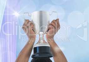 Cropped  image of hand holding trophy against bokeh