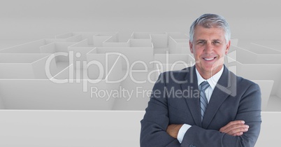 Digital composite image of businessman with arms crossed standing against maze