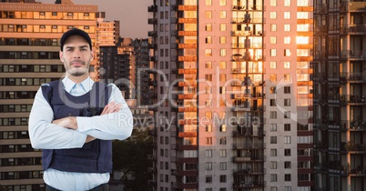 Portrait of confident security guard with arms crossed standing against buildings