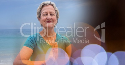 Senior women meditating on beach against sky