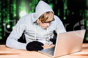 Hacker using a laptop with a green and black digital background