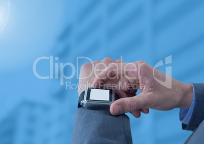 Businessman holding watch against blue buildings