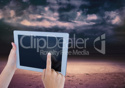 Hand touching tablet with dark cloudy sky