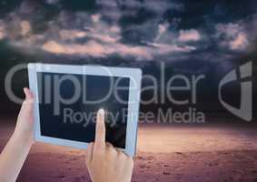 Hand touching tablet with dark cloudy sky
