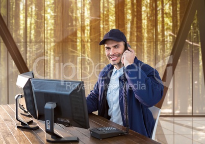 Security guard sitting in his office, is using technology, phoning and smiling