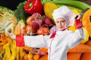 Cook chef is holding a knife against fresh vegetables background