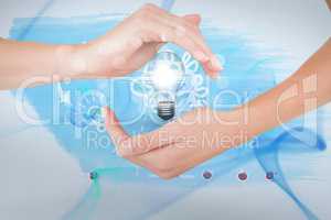 Hands holding bulb against blue background
