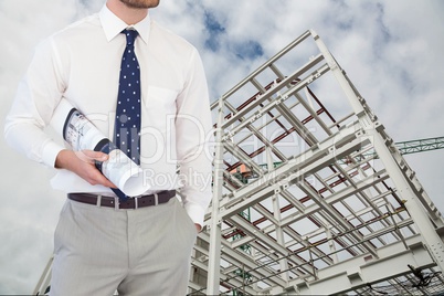 Architect with plans standing on in construction site