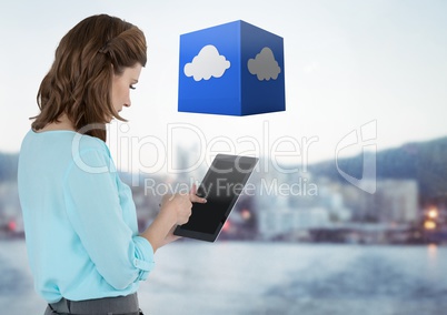 Businesswoman holding tablet with cloud cube with distant city background