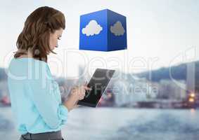 Businesswoman holding tablet with cloud cube with distant city background