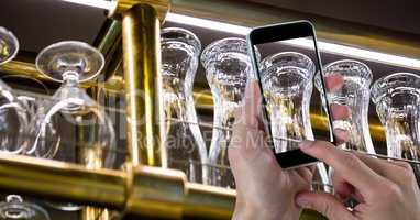 Low angle view of hand taking picture of glasses through smart phone at bar