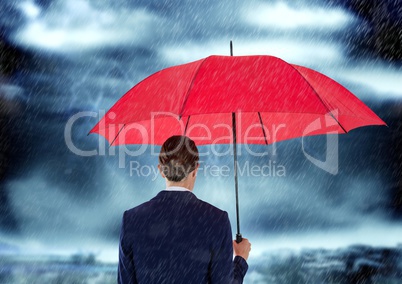 Rear view of businesswoman carrying red umbrella in rainy sesaon