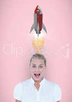 Portrait of shocked  woman with rocket launch over head against pink background