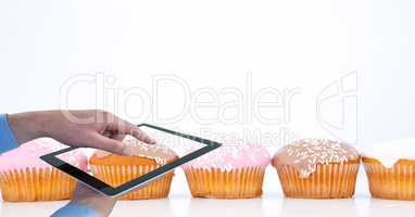 Cropped hands photographing muffins through digital tablet