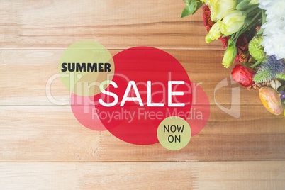 Red and green circular sale graphic on table with flowers