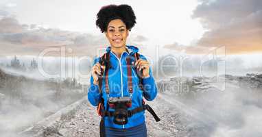 Hipster carrying backpack and camera standing on road against sky